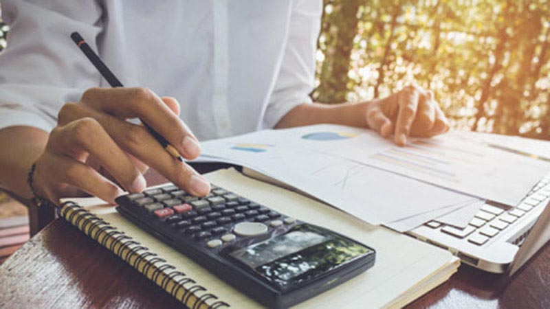 Person sitting at a desk with papers and a calculator.