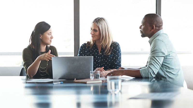 A small group of business people have a discussion at a table.