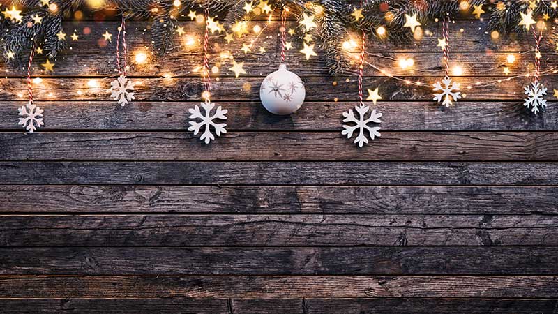 Holiday ornaments and lights hung on a wooden block.