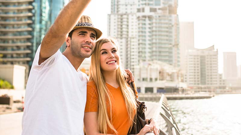 A young couple sightsee on a walkway near the marina in Dubai.